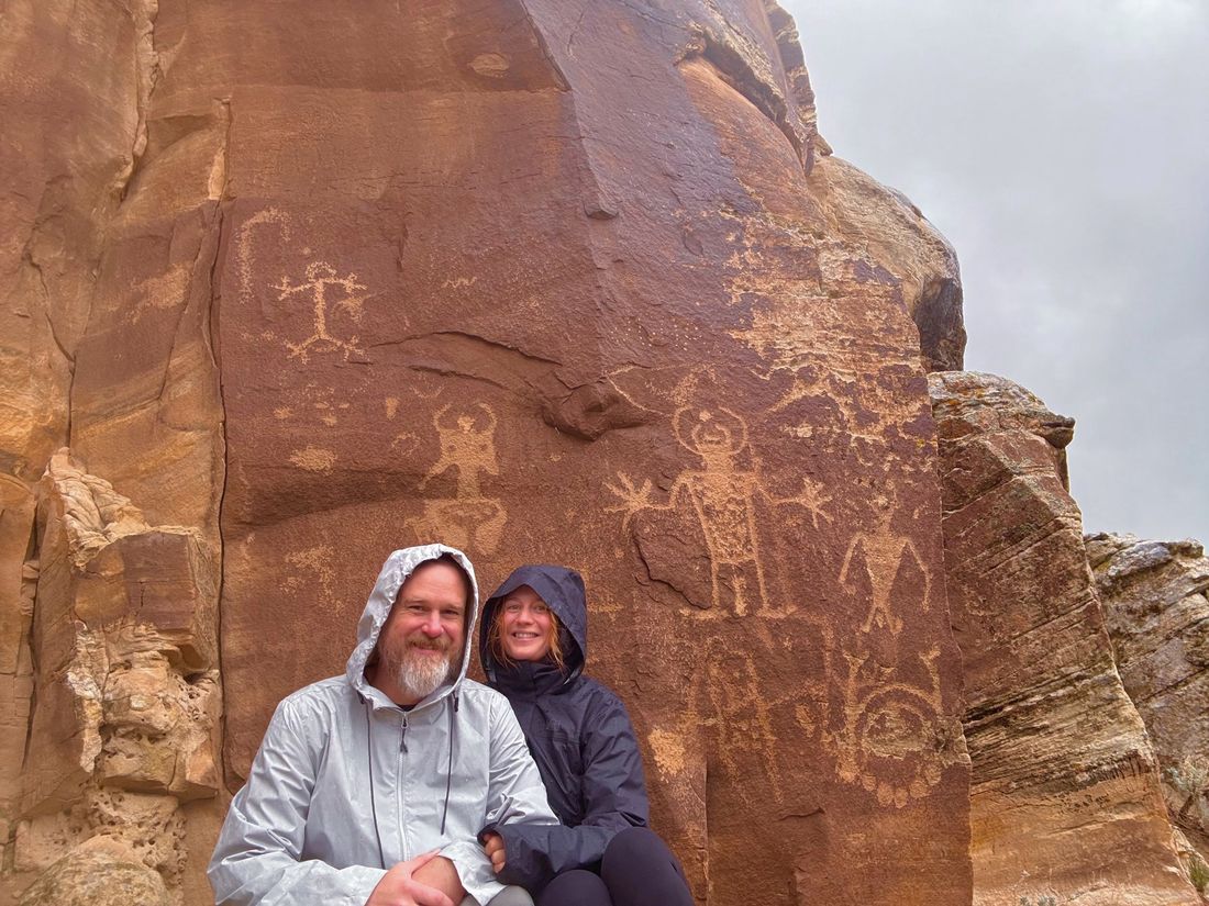 Jesse and Becky in rain jackets by a petroglyph panel