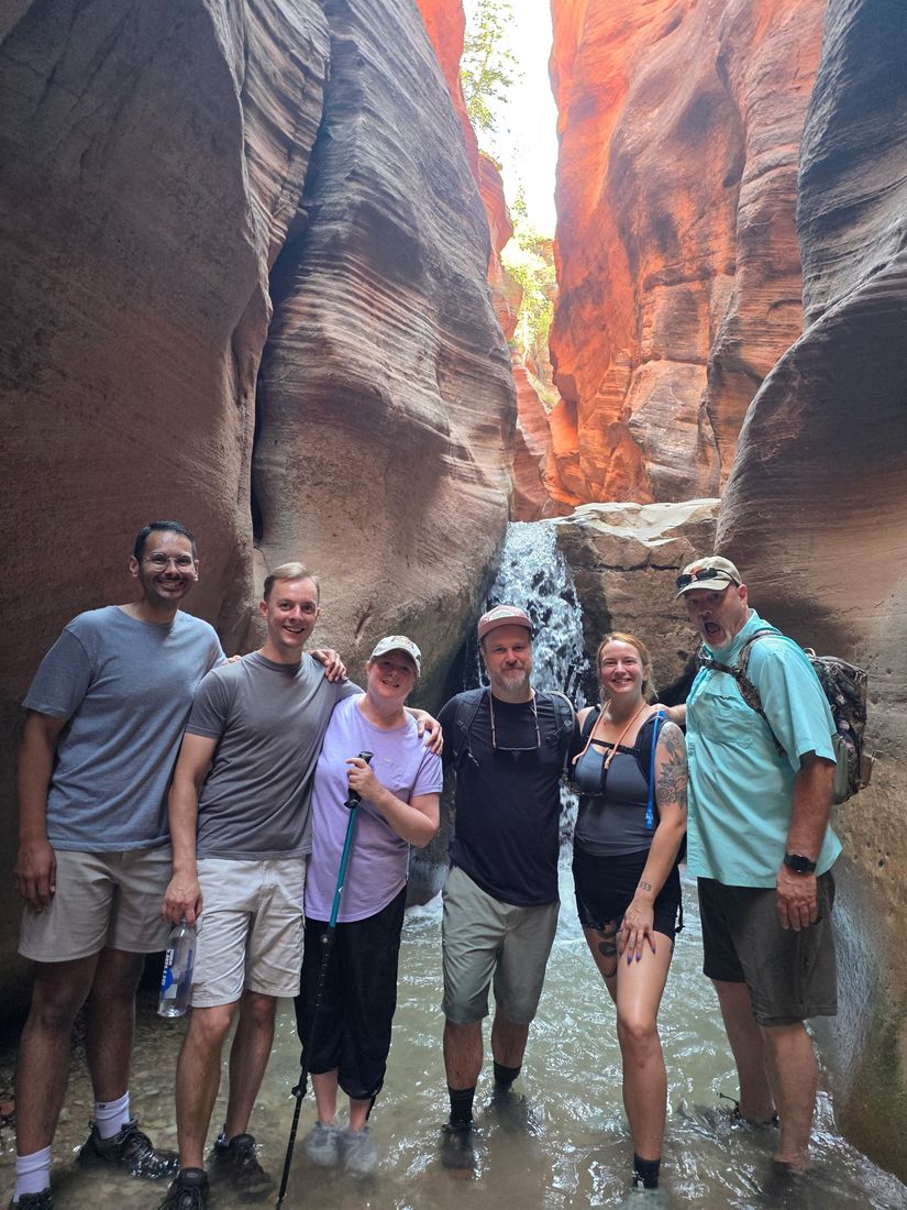 Hiking group in a slot canyon by a small waterfall